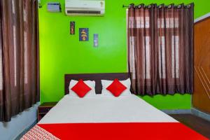 a green bedroom with a bed with red pillows at Flagship Hotel Heaven Inn in Patna