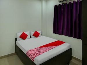 a bed with red pillows in a room at Flagship Hotel The Guest Land in Visakhapatnam
