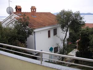 ein weißes Haus mit rotem Dach und einem Zaun in der Unterkunft Apartments Pero in Kožino