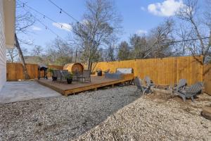 a backyard with a wooden patio with chairs and a fence at 5th St Getaway w Sauna Hot tub Firepit & Game Room in Waco
