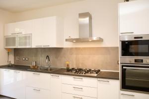 a kitchen with white cabinets and a sink and a stove at B&B Zvana's - Da Giovanna in Imola