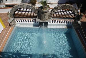 a swimming pool with a fountain in a house at Hotel Punto Azzurro in Ischia