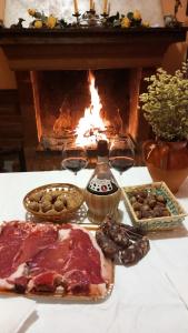 una mesa con comida y copas de vino y una chimenea en Il Sentiero Bed & Breakfast, en Vicalvi