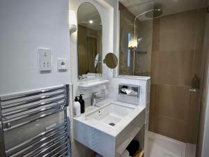 een witte badkamer met een wastafel en een spiegel bij Hotel De Verdun 1882, BW Signature Collection in Lyon