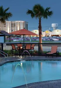 a pool with chairs and a table and a palm tree at Hampton Inn and Suites Marksville in Mansura