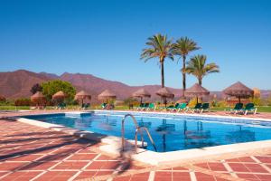 a swimming pool with chairs and palm trees and mountains at Beautiful luxurious 2 bedroom apartment with a breathtaking view at La Cala Golf in La Cala de Mijas