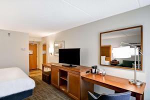 a hotel room with a desk with a bed and a mirror at Hampton Inn Albany-Wolf Road in Albany