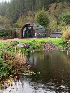 a circular building next to a body of water at Red Squirrel Pod with Hot Tub in Oban