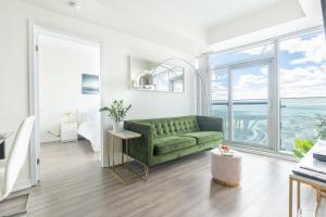 sala de estar con sofá verde y ventana grande en Beautiful Luxurious Modern Condo With Breathtaking Views, en Toronto