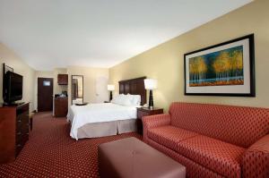 a hotel room with a bed and a red couch at Hampton Inn Atlanta-Stockbridge in Stockbridge