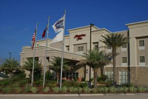 a hotel with three flags in front of it at Hampton Inn Orange in Orange