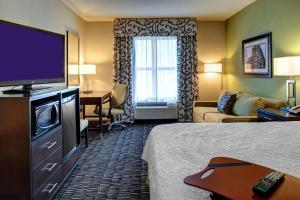 a hotel room with a bed and a flat screen tv at Hampton Inn & Suites Baton Rouge Downtown in Baton Rouge