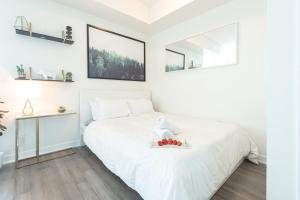 a white bedroom with a bed with a bowl of fruit on it at Beautiful Luxurious Modern Condo With Breathtaking Views in Toronto
