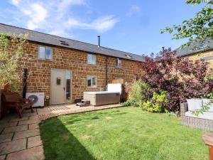 a backyard of a brick house with a lawn at Cow Byre in Little Tew