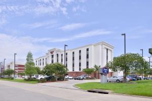 a white building with cars parked in a parking lot at Hampton Inn Gonzales in Gonzales