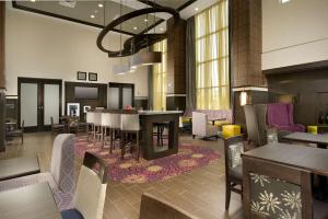 Hampton Inn & Suites - Buffalo Airport في تشيكتاواغا: لوبي الفندق مع منطقة طعام مع طاولات وكراسي