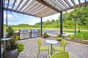 eine Terrasse mit Tischen, Stühlen und einem Grill in der Unterkunft Home2 Suites By Hilton Opelika Auburn in Opelika