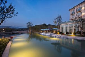 a swimming pool with white chairs next to a building at Hilton Garden Inn Hangzhou Lu'Niao in Anji