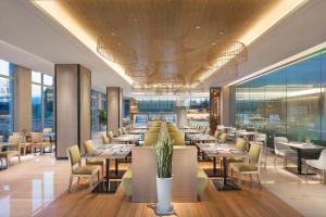 une salle à manger avec des tables et des chaises dans un restaurant dans l'établissement Hilton Garden Inn Hangzhou Lu'Niao, à Anji
