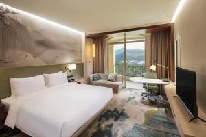 een hotelkamer met een groot wit bed en een bureau bij Hilton Garden Inn Hangzhou Lu'Niao in Anji