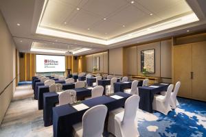 una sala de conferencias con mesas, sillas y una pantalla en Hilton Garden Inn Nujiang, en Lushui