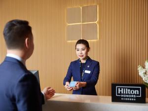 un hombre y una mujer de pie en un escritorio en Hilton Garden Inn Anshan, en Anshan