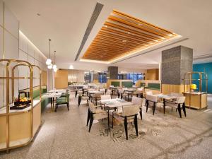 a restaurant with tables and chairs in a room at Hilton Garden Inn Anshan in Anshan
