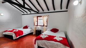 - une chambre avec 2 lits et des couvertures rouges et blanches dans l'établissement APARTAHOTEL CASA DE ANGEl 4, à Villa de Leyva