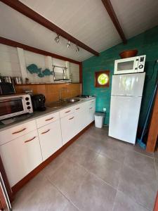 Una cocina con un refrigerador blanco y un microondas. en Bungalow, gîte les fleurs du colibri, en Bouillante 7 fotos más