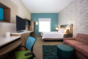 a hotel room with a bedroom with a bed and a couch at Home2 Suites by Hilton Pflugerville, TX in Pflugerville