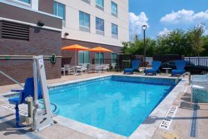 a swimming pool with chairs and umbrellas next to a building at Hampton Inn & Suites Cedar Park North Austin, Tx in Cedar Park
