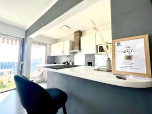 une cuisine avec une chaise bleue à côté d'un comptoir dans l'établissement Le Best View, Climatisé vue mer panoramique, Parking gratuit, WIFI, à Menton 4 autres photos