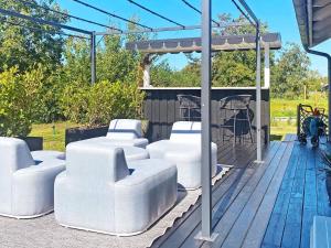 a group of white chairs on a wooden deck at 8 person holiday home in R dby in Rødby
