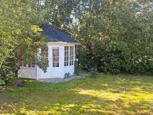 a small white shed in a yard at 8 person holiday home in R dby in Rødby