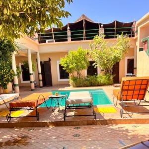 ein Pool mit Stühlen und ein Tisch neben einem Haus in der Unterkunft Riad Rime Garden Marrakech in Marrakesch