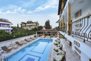 a pool on the side of a building with chaise lounge chairs at Amore Hotel Teki̇rova in Tekirova