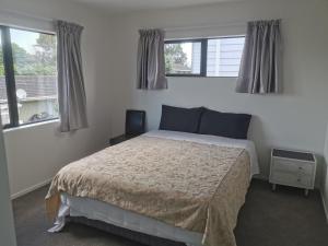una camera con un letto e due finestre di Lovely House in Central Papatoetoe ad Auckland