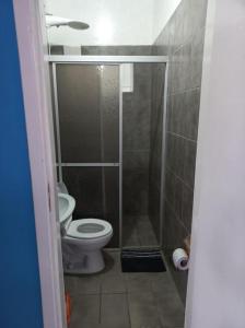a small bathroom with a toilet and a shower at Suíte Barros in Navegantes