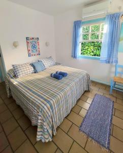 a bedroom with a bed with blue pillows and a window at Pousada Los Casarones in Florianópolis