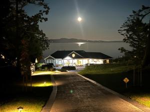 Ocean Front Private Suite في فيكتوريا: منزل به قمر على بحيرة في الليل