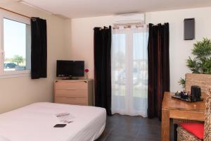 a bedroom with a bed and a tv and a window at Hôtel Domaine le Milos in Castries