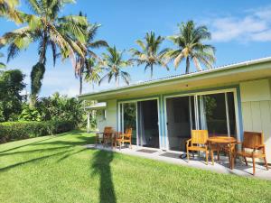 ein Haus mit Stühlen und einem Tisch auf einem Rasen in der Unterkunft Arnott's Lodge & Hiking Adventures in Hilo