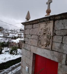 a brick building with a red door and a cross at Casa do Loureiro - Apartamento in Paradela