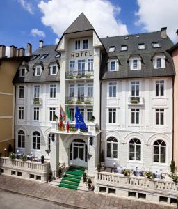 Cet hôtel occupe un bâtiment blanc arborant des drapeaux. dans l'établissement Hotel Croce Bianca, à Asiago