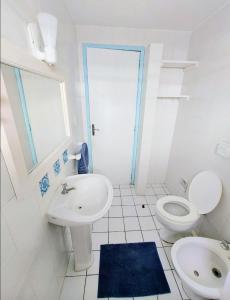 Baño blanco con lavabo y aseo en Pousada Los Casarones, en Florianópolis