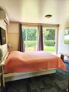 sypialnia z łóżkiem i dużym oknem w obiekcie Arnott's Lodge & Hiking Adventures w mieście Hilo