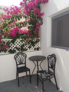 two chairs and a table with pink flowers on a wall at SPILIOTICA VILLAS AND APARTMENTS in Imerovigli