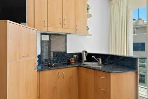 a kitchen with wooden cabinets and a sink at Top Floor Beachside Apartment in the Heart of Mooloolaba in Mooloolaba