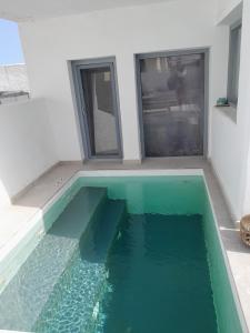 a swimming pool with green water in a house at SPILIOTICA VILLAS AND APARTMENTS in Imerovigli