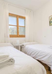 um quarto branco com 2 camas e uma janela em Selva Blanca de Villanua em Villanúa